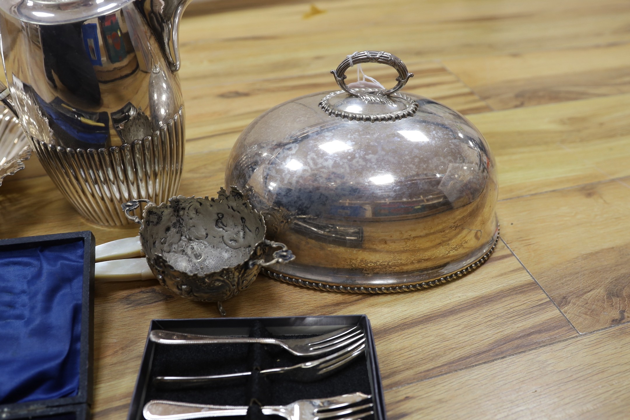 A cast white metal bowl and a collectio of plated items including a hot water pot, meat cover, cased flatware, etc.